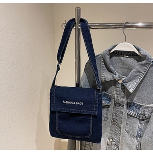 Dettaglio della borsa a tracolla in denim blu scuro con testo bianco e tracolla regolabile