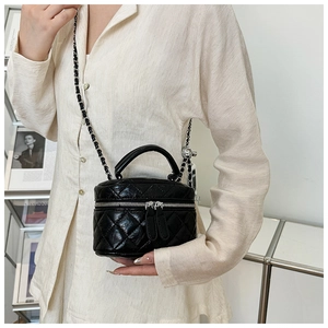 Détail d'un mini sac seau noir matelassé avec bandoulière chaîne porté par un mannequin