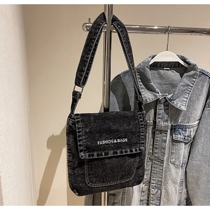 Dettaglio della borsa a tracolla in denim nero lavato con ricamo bianco fashion