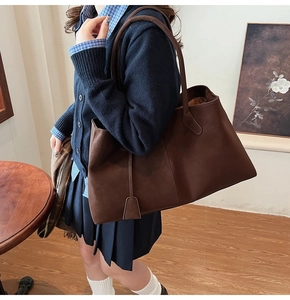 Detail view of a large brown matte tote bag with thin straps on a female model