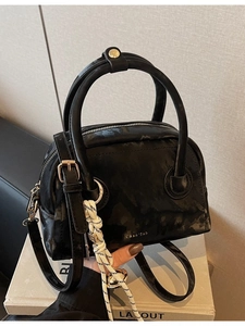 Glossy black patent leather handbag with gold logo and marble texture for casual style