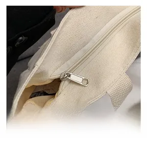Nahaufnahme des hochwertigen Metallreißverschlusses und der Hardware an der weißen Canvas-Tasche