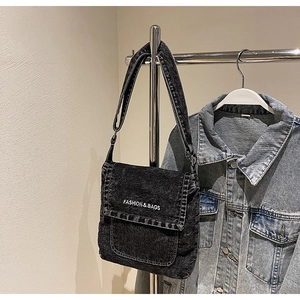 Dettaglio borsa a tracolla in denim nero lavato con scritte bianche e tracolla regolabile