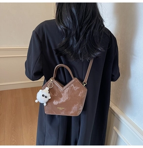 Détail d'un sac seau marron à texture marbrée avec breloque en peluche blanche et coupe en V