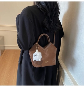Détail du sac seau marron foncé en forme de V avec breloque peluche et dorures