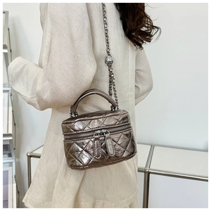 Vue détaillée du mini sac seau matelassé bronze avec chaîne sur le mannequin