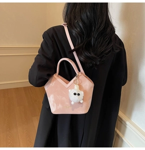 Détail du sac seau rose avec ouverture en V et breloque petit monstre en peluche douce