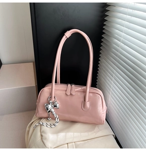 Détail du sac Boston rose montrant le similicuir lisse et le pendentif nœud argent