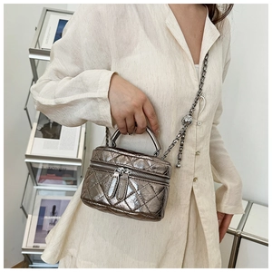 Mini sac seau matelassé argent métallique avec bandoulière porté par un mannequin