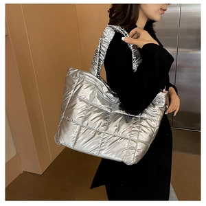 Detail of silver quilted puffer tote bag featuring metallic finish and ruffled shoulder strap