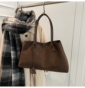 Detail of dark brown tote bag with matte texture and minimalist leather triangle tag