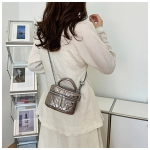Mini sac argenté à matelassage losange porté en bandoulière par un mannequin avec une chaîne