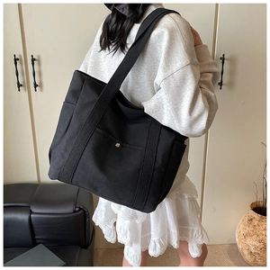 Side view of large black canvas tote bag with metal buckle pocket for daily commute