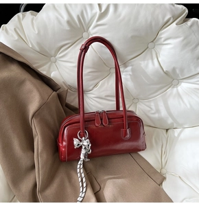 Détail du sac Boston bordeaux avec breloque nœud argenté et doubles fermetures éclair