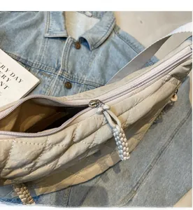 Detail of light beige quilted bag showing smooth zipper and woven cord puller