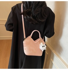 Sac seau rose avec coupe en V et breloque en peluche sur un manteau noir vue de dos
