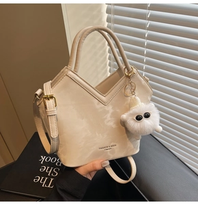 Détail du sac à main crème en forme de V avec texture nuage et charm en peluche
