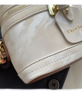 Gros plan sur la texture marbrée et les finitions dorées du sac à main beige