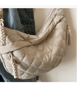 Close-up of beige quilted rhombus shoulder bag with woven zipper pull detail