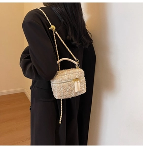 Detail of tweed crossbody bag with gold chain strap and textured woven fabric