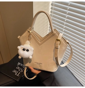 Détail du sac seau crème avec ouverture en V et charmant pendentif en peluche