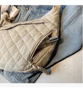 Detail of beige quilted hobo bag side pocket showing storage capacity for perfume