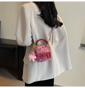 Detailed macro view of a pink tweed box bag with golden chain and plush charm accessory