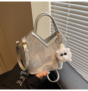 Détail du sac à main argenté texture marbre avec breloque monstre en peluche douce