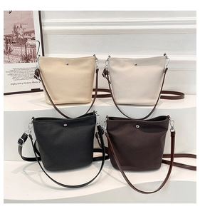 Vue détaillée de quatre sacs seaux tissés en beige, blanc, noir et marron sur un socle