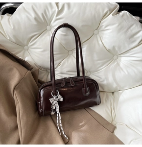 Détail du sac Boston marron foncé brillant avec breloque nœud argenté élégant