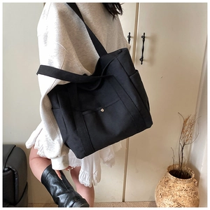Detail of a black large-capacity canvas tote bag featuring silver metal buckle pockets