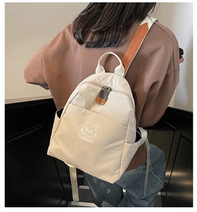 Rear view of a beige nylon backpack with a cat print on a model for scale