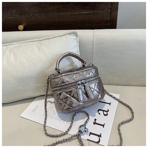 Détail d'un mini sac matelassé métallisé avec double zip et bandoulière sur canapé