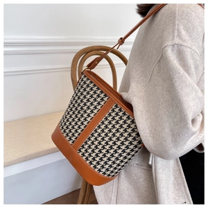 Détail du sac seau à motif pied-de-poule avec bordure en cuir marron et boucle dorée