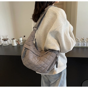 Close-up of gray quilted crescent bag with adjustable strap and braided zipper detail