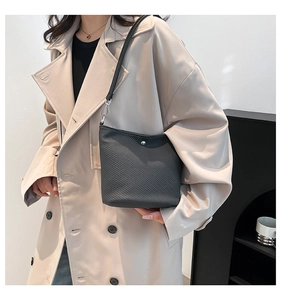 Détail d'un sac seau noir texturé avec finitions argentées porté par un mannequin