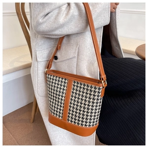 Détail du sac seau rétro à motif pied-de-poule avec bordure en cuir et boucles dorées