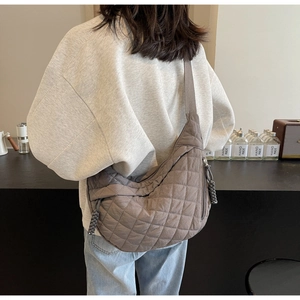 Close-up of diamond-quilted nylon fabric and woven zipper pull on the dark taupe bag