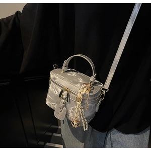 Gros plan du mini sac boîte gris argenté avec texture marbre et breloques dorées