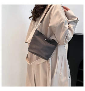 Détail d'un sac bandoulière marron texturé avec bouton pression argenté et fine lanière