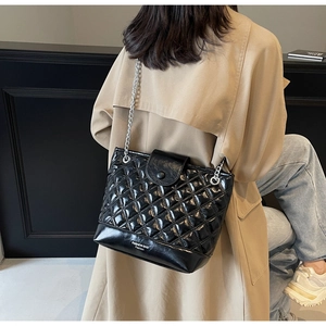 Detail of black quilted bucket bag with silver chain strap and fashion text at the bottom