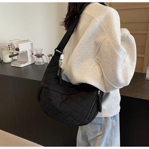 Detail of a black quilted hobo bag with adjustable wide strap shown in a lifestyle setting
