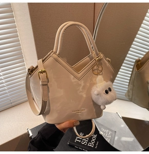 Détail du sac seau en cuir PU beige avec coupe en V et breloque monstre en peluche