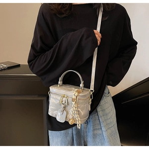 Vue détaillée d'un sac vanity gris avec finitions dorées et pendentif foulard rayé
