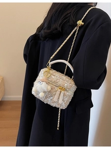 Chic cream woven tweed crossbody bag with plush charm and chain strap on a black blazer