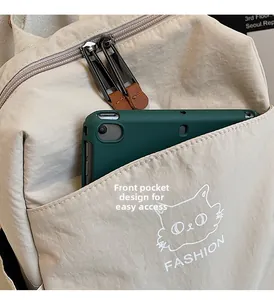 Detail of beige nylon backpack front pocket with cat logo and green tablet inside