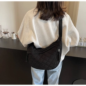 Quilted black hobo bag with diamond stitching shown on model in a modern interior