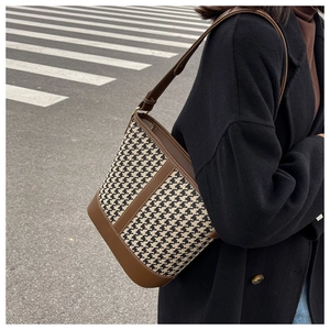 Sac seau à motif pied-de-poule porté en bandoulière sur fond de rue urbaine moderne