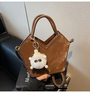 Détail du sac seau marron foncé avec design en V et charmant monstre en peluche doux