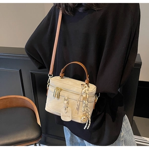 Détail du sac bandoulière beige avec poignées en cuir marron et zips dorés
